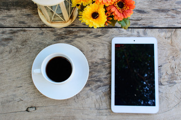 coffee, tablet on wooden table with flower