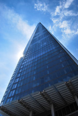 The Shard of Glass London towers into blue sky with sun