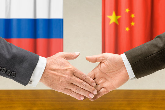 Vertreter Russlands und Chinas reichen sich die Hand