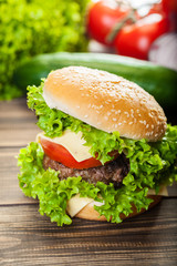 Cheeseburger with lettuce, onions and tomato in a sesame bun
