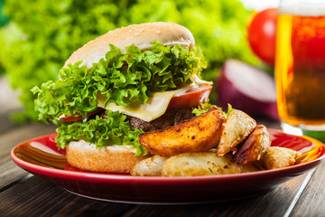 Cheeseburger with fried potatoes on a plate with beer