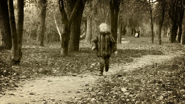 Alone little boy joyful bouncing walking in autumn park