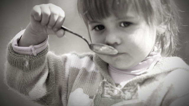 Black and White portrait : Cute Little girl eats with spoon