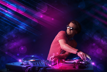 Plakat Young DJ playing on turntables with color light effects