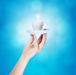 Hand holding red cup on blue background