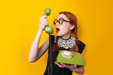 Redhead girl with green phone on yellow background.