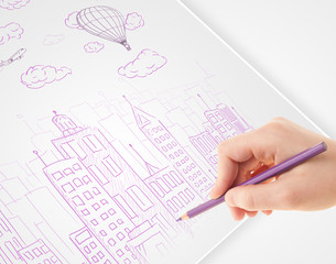 A person drawing sketch of a city with balloons and clouds on a