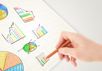 Business person drawing colorful graphs and icons on paper