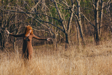 Young woman walking in golden dried grass field