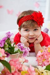 Fototapeta premium Девочка с красным бантиком в цветах
