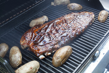 A rack of barbecue ribs cooking on a grill