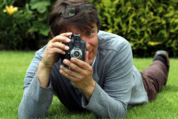 Alter Fotoapparat, Mann auf Wiese macht Foto