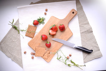 Cut strawberrries and cookies on a wooden carving board