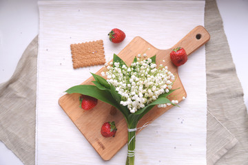 White lily of the valley bouquet on a wooden caving board