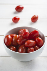 Bowl con tomates cherry en la mesa de madera blanca de la cocina