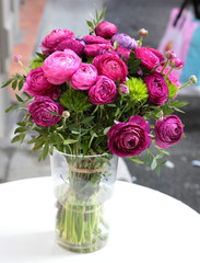Bouquet of violet ranunculus flowers in glass vase on the table