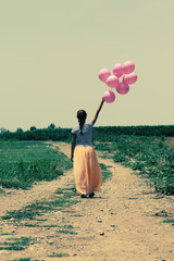 Młoda kobieta gospodarstwa różowe balony i chodzenie na łące. Zdjęcie - 65684063
