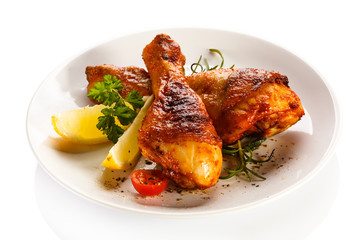 Grilled chicken legs and vegetables on white background