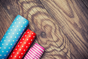 Fototapeta na wymiar Rolls of colored wrapping paper on wooden background