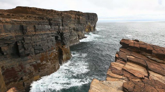 Huge waves crash against sea cliffs in Orkney, Scotland