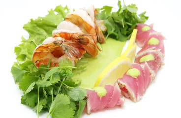 shrimp and tuna with greens and sauce on a white background