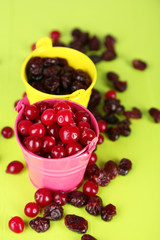 Fresh and dry cranberry in pails on wooden table close-up