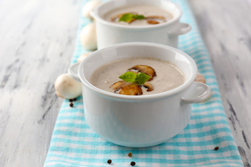 Mushroom soup in white pots, on napkin,  on wooden background