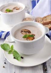 Mushroom soup in white pots, on napkin, on wooden background
