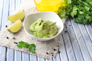 Fresh guacamole in bowl on wooden table