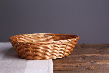 Empty wicker basket on wooden table, on dark background