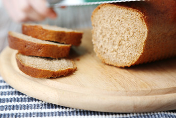 Female hands cutting bread on wooden board, close-up