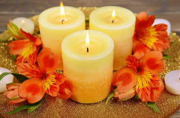 Fototapeta na wymiar Beautiful candles with flowers on table on brown background