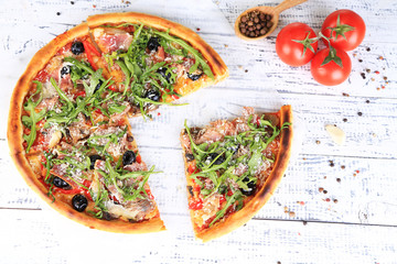 Pizza with arugula on color wooden background