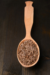 Spice cumin in spoon on wooden background