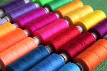 Multicolor sewing threads on wooden background