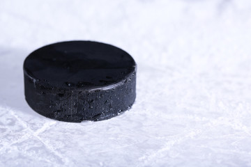 Black hockey puck on ice rink background