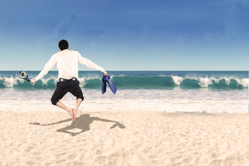 Backside of businessman jumping on beach