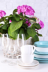Blooming hydrangea and utensils on table on grey wall
