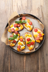 Tasty bruschetta with tomatoes on pan, on old wooden table