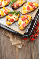 Tasty bruschetta with tomatoes on pan, on old wooden table