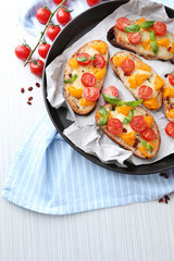 Tasty bruschetta with tomatoes in pan, on table