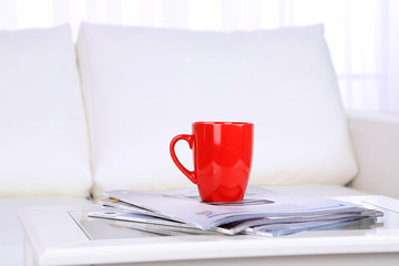 Magazines and cup on coffee table in room