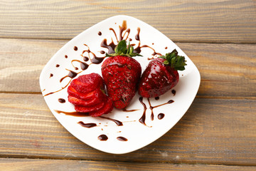 Red ripe strawberries with chocolate on wooden table