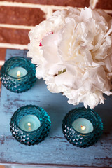 Glass candlesticks and flowers on stand, on bricks background