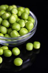 Fresh green peas in bowl isolated on black background