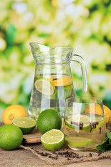 Fresh summer drink with lime and cloves in glass and jug,