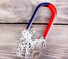 Magnet and  chain on color wooden background