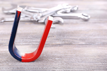 Magnet and wrenches on color wooden background