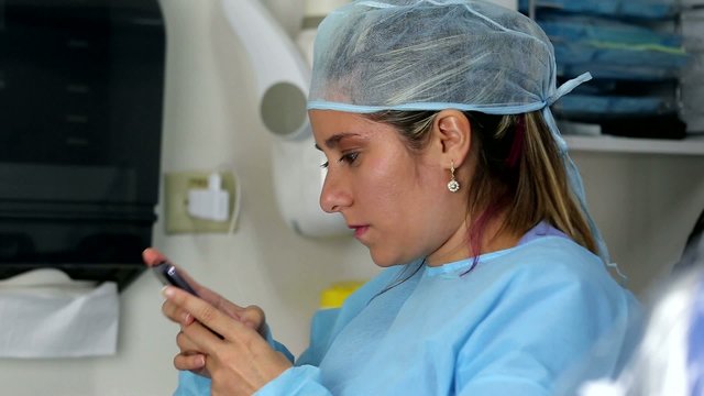 female surgeon reading message at mobile phone