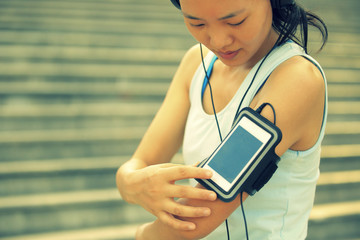 woman runner listening to music in headphones from smart phone